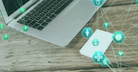 Image of medical icons spinning over close up of a laptop on wooden surface. medical research and...