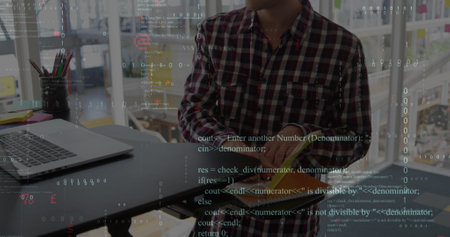 A business creative is working on a laptop computer in a modern office, making notes. Global business finances data processing and connections concept digitally generated image.の写真素材