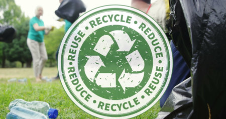 Image of recycling icon over volunteers cleaning in park. global environment, green energy and...