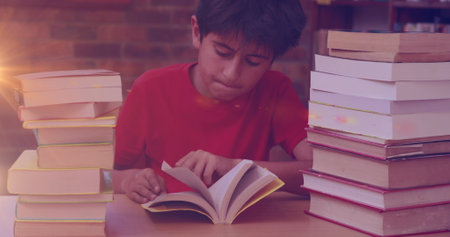 Image of light trails over biracial boy reading books. children's book day and celebration concept digitally generated image.の写真素材