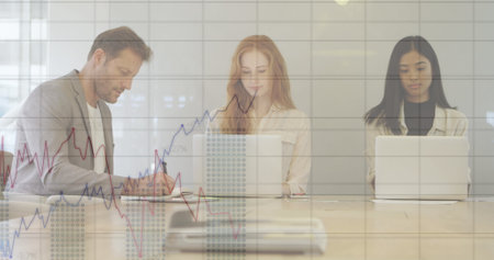 Image of financial data processing over diverse business people using laptops at meeting. Global business, communication, finances and digital interface concept digitally generated image.の写真素材