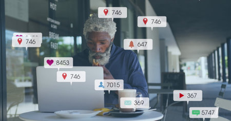 Image of social media icons and numbers over african american businessman with laptop. Global social media, business, connections, computing and data processing concept digitally generated image.の写真素材