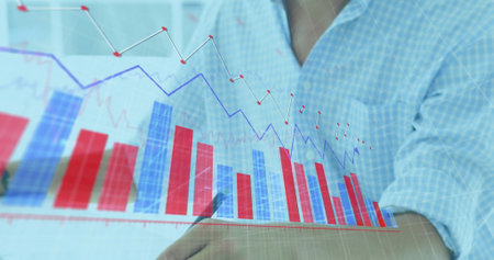 Image of graphs moving over caucasian businessman drawing on graphics tablet and using computer....