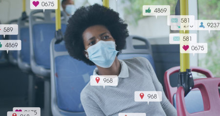 Image of social media icons and data over african american woman in face mask. Global finance, business, connections, computing and data processing concept digitally generated image.の写真素材