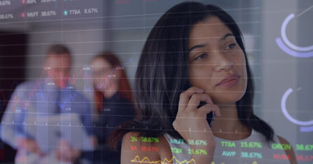 Image of graphs and trading board over beautiful biracial woman talking on smartphone. Digital composite, multiple exposure, report, business, stock market and technology concept.の写真素材