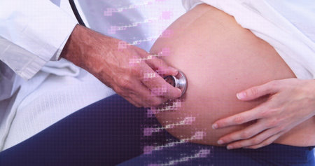 Caucasian midwife and doctor examining pregnant belly, both in white coats. They're focusing on...