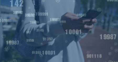 Image of changing numbers and connected icons over midsection of biracial man using cellphone....