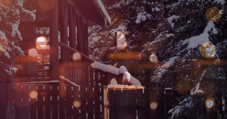 Snow covering trees and cabin, lights glowing warmly. Soft snowflakes falling, creating a peaceful winter atmosphereの写真素材