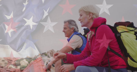 Image of flag of united states of america over senior couple taking break hiking in mountains....