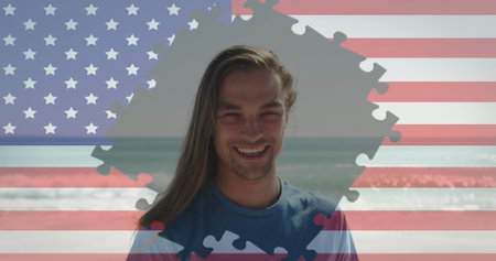 Jigsaw puzzle over american flag against portrait of caucasian man smiling at the beach. american independence patriotic holiday conceptの写真素材