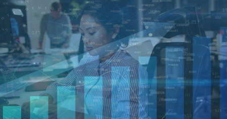Asian woman and Caucasian colleagues working on computers in office. Transparent graphs and charts overlaying scene, showing data analysis and trendsの写真素材
