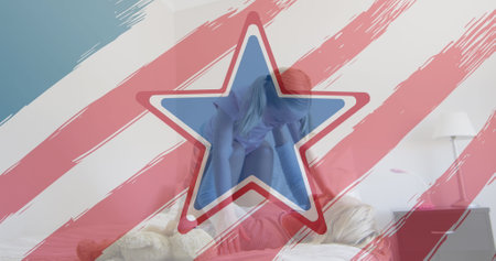 American flag design pattern and pulsating stars over caucasian mother and daughter playing on bed. american independence and celebration conceptの写真素材