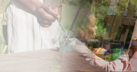 Image of african american woman painting on easel in garden. Art, hobby and nature concept digitally generated imageの写真素材