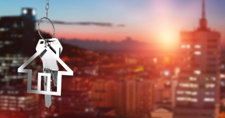 Image of hanging house keys against aerial view of cityscape with tall buildings. Relocation and real estate conceptの写真素材