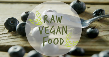 Image of raw vegan food text banner against close up of blue berries and spoon on wooden table. Vegan, organic and healthy food conceptの写真素材