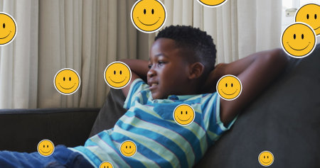 Image of emoji icons over happy african american boy lying. Social media and digital interface concept digitally generated image.の写真素材