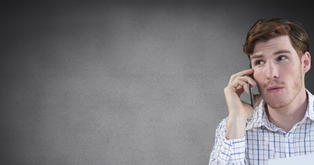 Image of caucasian man talking on smartphone against copy space on grey background. People, emotions and business technology conceptの写真素材