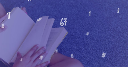 A schoolgirl is sitting on the floor in a library and reading a book. Business and patriotism concept digitally generated image.の写真素材