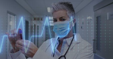 Image of heart rate montior against caucasian female doctor holding a vial bottle at hospital....