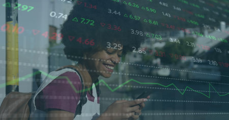 Image of trading board over smiling biracial woman chatting using smartphone. Digital composite, multiple exposure, business, abstract, stock market and technology concept.の写真素材