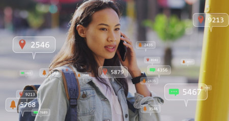 Image of social media data processing over asian woman using smartphone in city. Global computing, digital interface and data processing concept digitally generated image.の写真素材