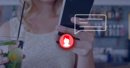 Image of neon profile and message icon against mid section of woman using smartphone at a bar. Global networking and business technology conceptの写真素材