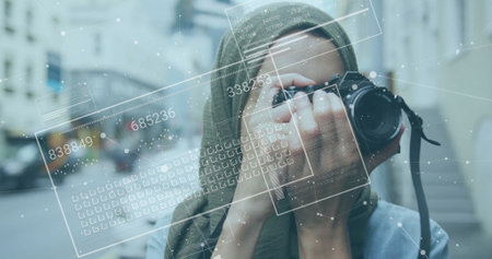 Image of financial data processing over biracial woman in hijab taking photos. Global finance, business, connections, computing and data processing concept digitally generated image.の写真素材