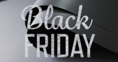 Image of black friday text over rolled up black paper on grey background. Black friday, cyber shopping, sales, retail and savings concept digitally generated image.の写真素材