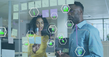 Image of icon in hexagons over diverse coworkers discussing reports on transparent board. Digital...