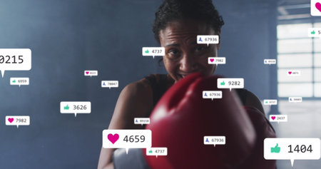 Image of notification bars over diverse female boxer looking at screen and practicing punches. Digital composite, multiple exposure, business, social media reminder and sports concept.の写真素材