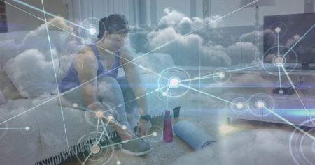 Image of network of connections over woman tying shoe laces and clouds. global sports, fitness and active lifestyle concept digitally generated image.の写真素材