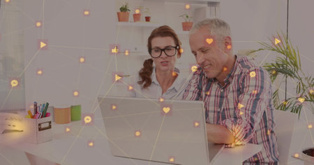 Network of digital icons against caucasian senior couple using laptop together at home. Global...