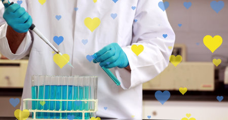 Image of yellow and blue hearts falling over midsection of biracial male lab worker. Science,...