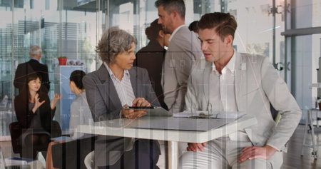 Image of multiple graphs, numbers over caucasian coworkers discussing reports on digital tablet. Digital composite, multiple exposure, business, planning, teamwork and technology concept.の写真素材