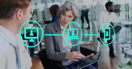 Image of network of icons over diverse businessman and businesswoman discussing at office. Global networking and business technology conceptの写真素材