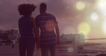 Image of light spots over biracial couple at beach. Holidays and digital interface concept digitally generated image.の写真素材