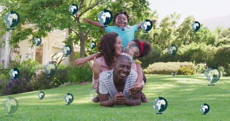 Image of globe icons over african american family in garden. Global ecology and digital interface concept digitally generated image.の写真素材