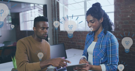 Image of light bulb icons and data processing over diverse business people. Global business, finances, computing and data processing concept digitally generated image.の写真素材