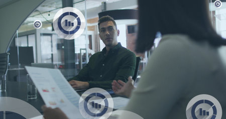 Image of digital icons over diverse business people in office. Global business, finances, computing and data processing concept digitally generated image.の写真素材