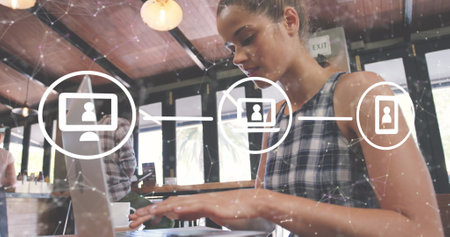 Image of network of connections with icons over african american woman using laptop. Global connections, technology and digital interface concept digitally generated image.の写真素材