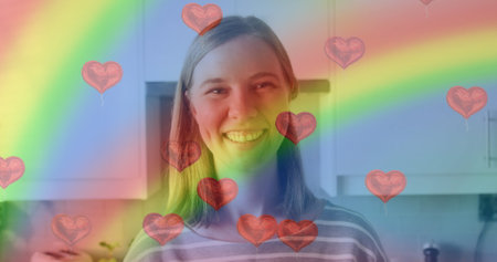 Image of heart emojis and rainbow flag over caucasian woman smiling. Lgbtq, love, romance and celebration concept digitally generated image.の写真素材