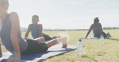 Image of light spots over happy diverse schoolboys stretching in outdoor yoga class. Health, wellbeing, school, childhood, education and learning, digitally generated image.の写真素材
