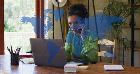 Image of numbers, map over biracial woman talking on cellphone and working on laptop at office....