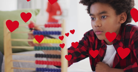 Image of social media heart icons over smiling biracial boy using abacus. global communication, connections and social media concept digitally generated image.の写真素材