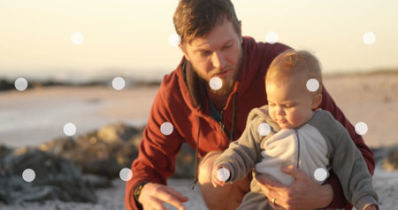 Image of white spots falling over caucasian father with baby. national weaning week and childhood concept digitally generated image.の写真素材