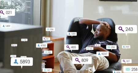 Image of social media icons over african american man looking out of window at home. Social media networking technology conceptの写真素材