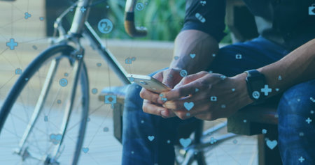Biracial young professional holding smartphone, sitting near bike. Wearing casual clothes, focusing on digital contentの写真素材