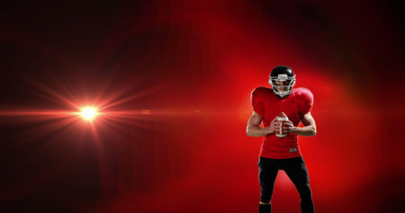 Image of excited american football player holding ball on red background with pulsing light. pro sports template concept with copy space, digitally generated image.の写真素材