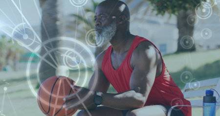 Image of network of connections over senior african american man with basketball at beach. healthy, active lifestyle, connections and digital interface concept digitally generated image.の写真素材