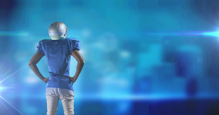 Image of rear view of waiting american football player on blurred blue with pulsing light. pro sports template concept with copy space, digitally generated image.の写真素材